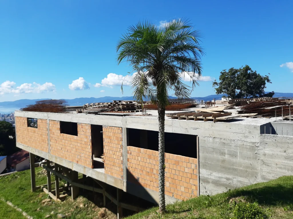 Estrutura de concreto da Casa J/M, no Bosque das Mansões, com palmeira e vista para a cidade